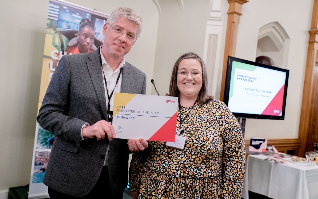 Two individuals holding a '2023 Employer of the Year' award certificate indoors.