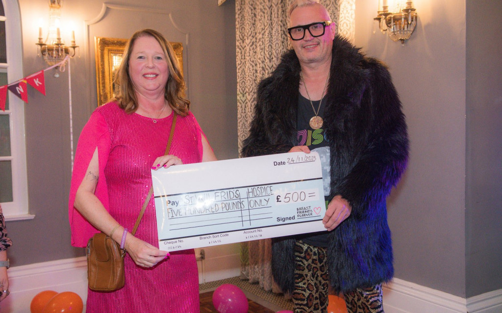 Two individuals holding a large ceremonial check for £500 to a hospice.