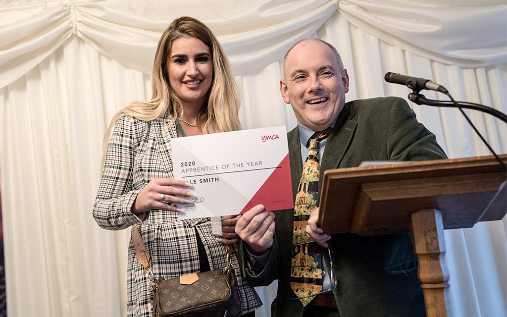 Elle Smith holding an 'Apprentice of the Year' certificate with another person at a podium.