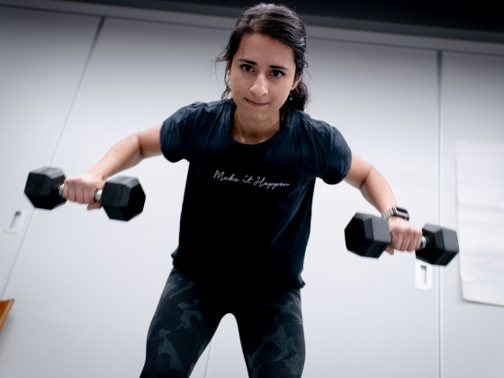 Person exercising with dumbbells in a gym.