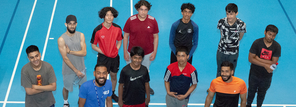 Group of people standing on an indoor track field.