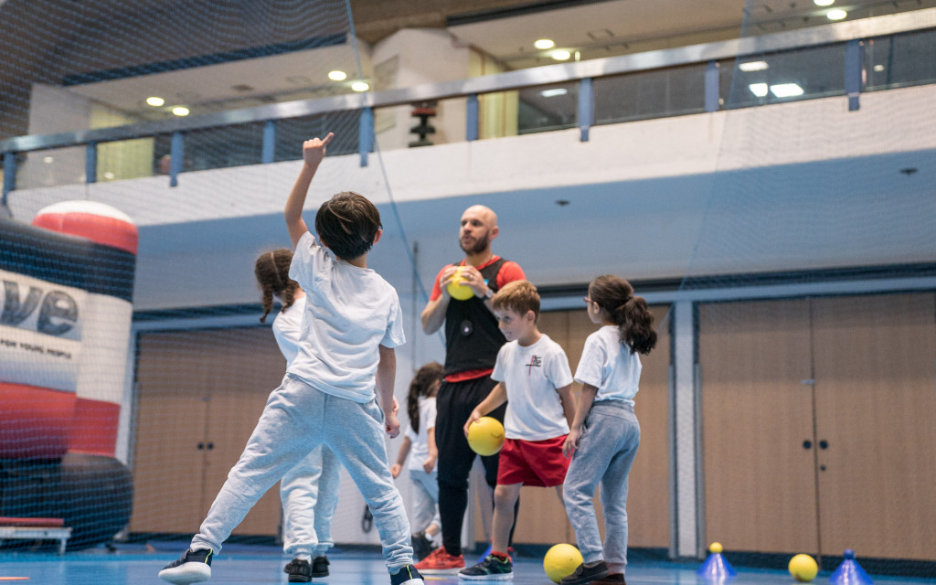 Children playing a ball game in a gymnasium.