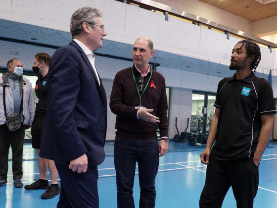 Group of people conversing in an indoor sports court.