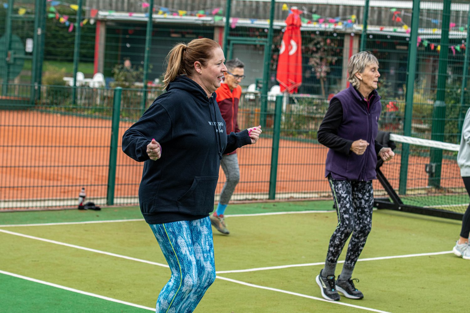 People doing outdoor exercises on a tennis court.